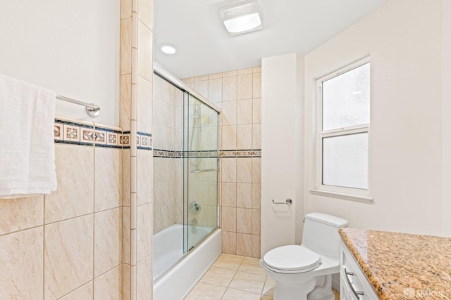 bathroom featuring toilet, tile patterned floors, enclosed tub / shower combo, and tile walls