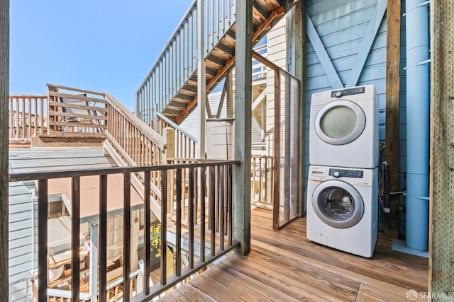 laundry area with stacked washer / drying machine, hardwood / wood-style floors, and laundry area