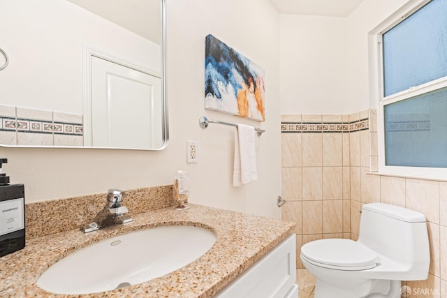 half bathroom featuring vanity, tile walls, and toilet