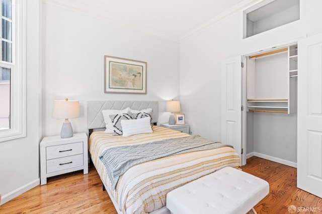 bedroom featuring ornamental molding, baseboards, and light wood finished floors