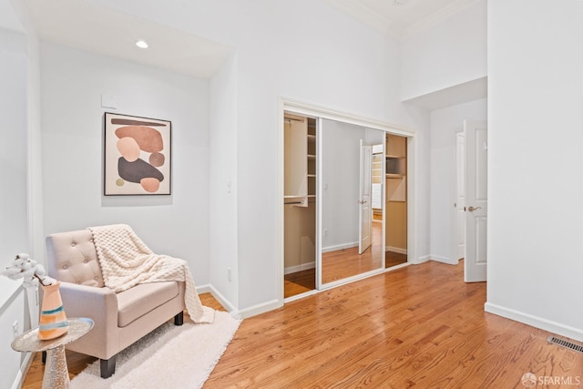 living area featuring visible vents, baseboards, crown molding, recessed lighting, and light wood-style flooring