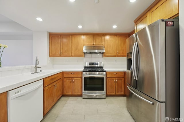 104 Diamond Cove Ter, San Francisco, CA 94134 - kitchen with stainless steel appliances, under cabinet range hood, brown cabinets, light tile patterned floors, and tile counters