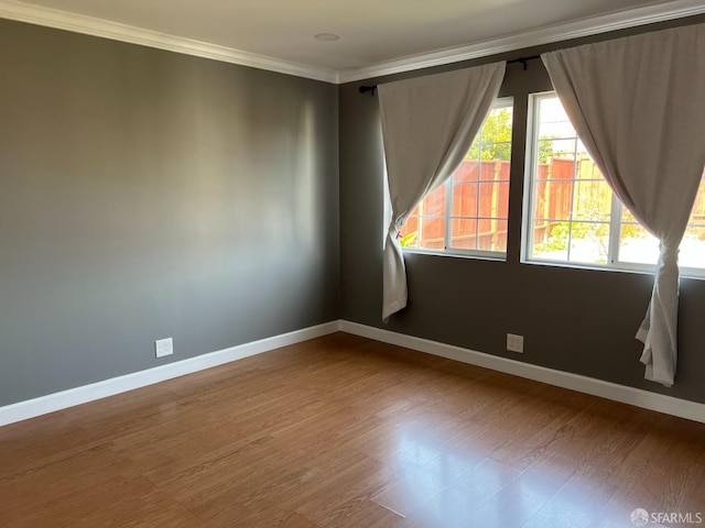 spare room featuring baseboards, wood finished floors, and ornamental molding