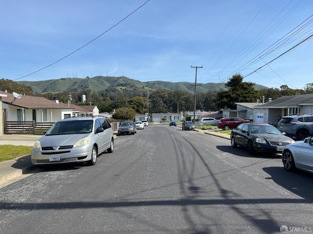 view of road featuring a residential view, a mountain view, and curbs