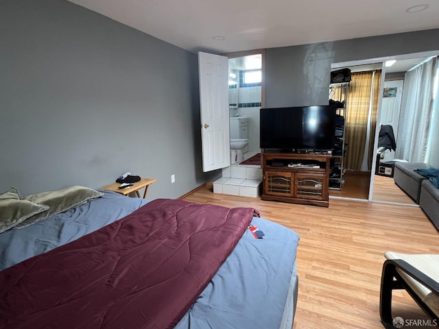 bedroom with ensuite bath and wood finished floors