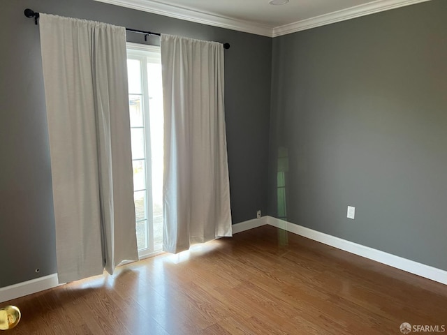unfurnished room featuring ornamental molding, baseboards, and wood finished floors
