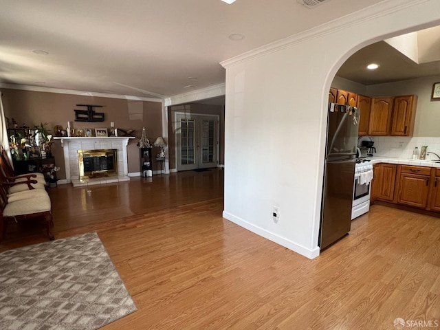 interior space with white gas stove, brown cabinets, light wood-type flooring, open floor plan, and freestanding refrigerator