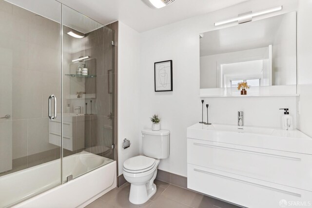 full bathroom featuring tile patterned flooring, vanity, combined bath / shower with glass door, and toilet