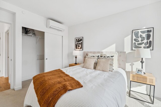 bedroom featuring a wall unit AC, light carpet, and a closet