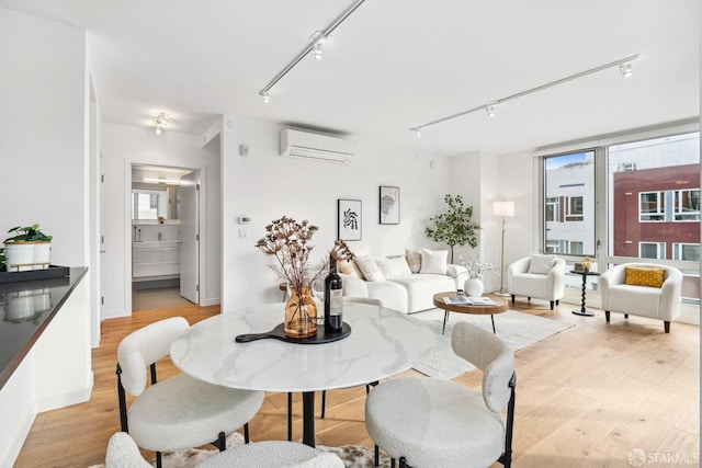 dining space with light wood-type flooring, rail lighting, and a wall mounted AC