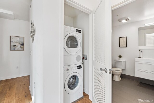 laundry area with wood-type flooring and stacked washer / drying machine