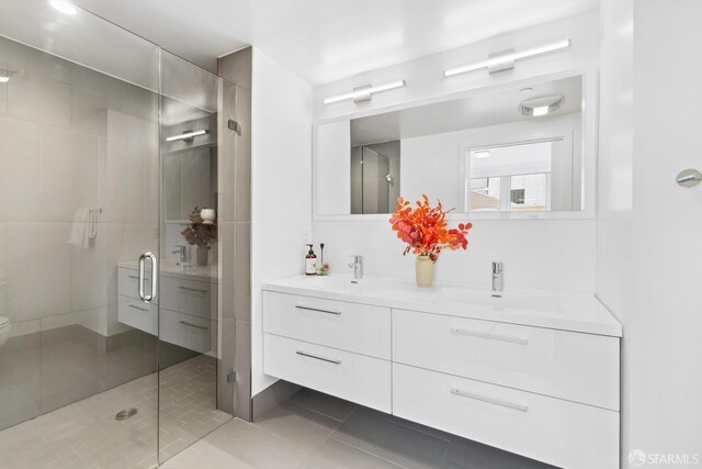 bathroom featuring tile patterned flooring, vanity, toilet, and a shower with door