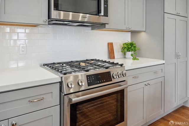 3511 23rd St Unit 1, San Francisco, CA 94110 - kitchen with appliances with stainless steel finishes, light countertops, gray cabinets, decorative backsplash, and light wood-style floors