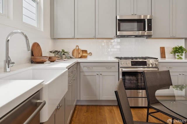 3511 23rd St Unit 1, San Francisco, CA 94110 - kitchen with stainless steel appliances, decorative backsplash, wood finished floors, and light countertops