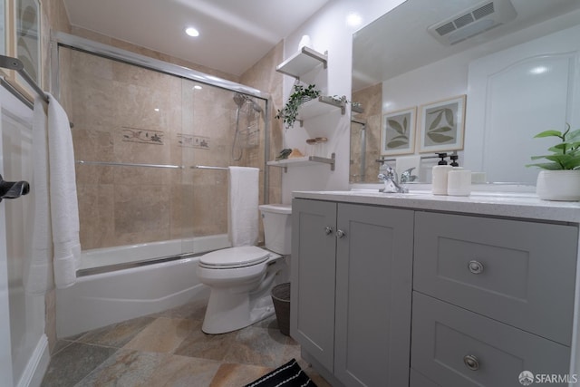 full bathroom featuring vanity, toilet, and bath / shower combo with glass door