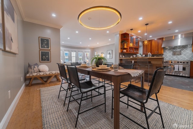 dining area with ornamental molding and light hardwood / wood-style floors