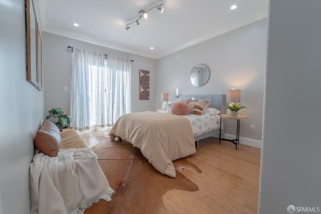 bedroom with ornamental molding, track lighting, and light hardwood / wood-style floors