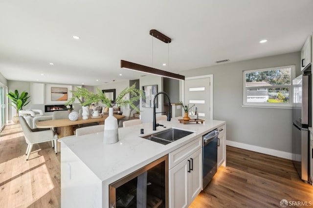 kitchen with a sink, open floor plan, stainless steel appliances, light wood-style flooring, and baseboards
