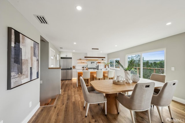 dining area with baseboards, light wood finished floors, visible vents, and recessed lighting