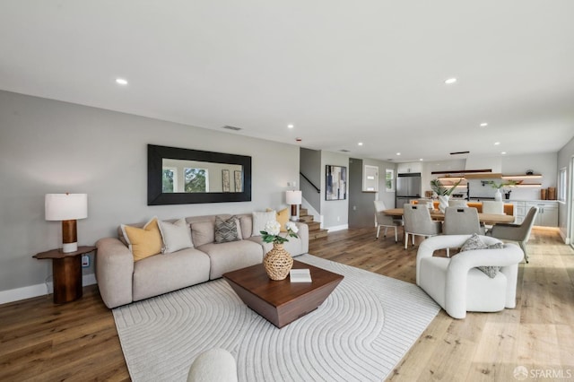 living room with light wood-style flooring, recessed lighting, and stairway