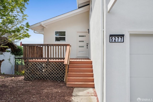 entrance to property with stucco siding and a wooden deck