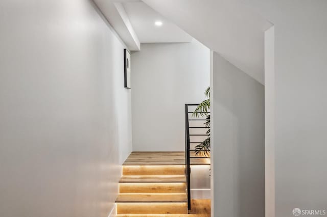 stairs featuring wood finished floors and recessed lighting