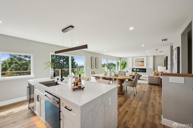 kitchen featuring white cabinets, light wood-style flooring, a sink, visible vents, and dishwasher