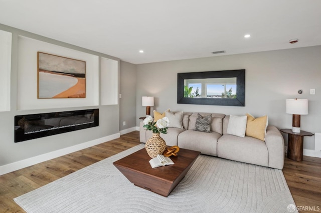 living room with baseboards, wood finished floors, visible vents, and recessed lighting