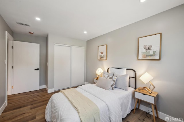 bedroom with baseboards, wood finished floors, and visible vents