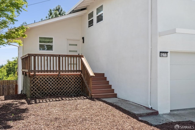exterior space with stucco siding, a deck, fence, and a garage