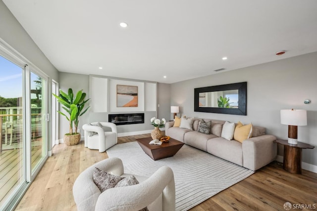 living area featuring baseboards, light wood-style floors, visible vents, and recessed lighting
