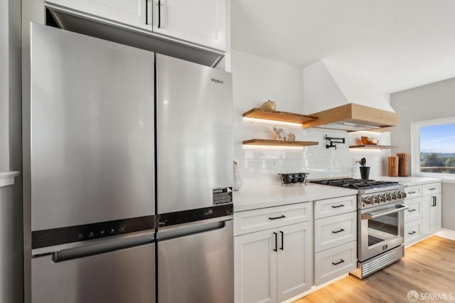 kitchen featuring white cabinets, high end range, open shelves, tasteful backsplash, and custom exhaust hood