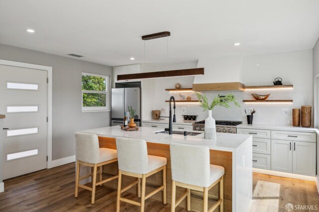 kitchen with open shelves, freestanding refrigerator, premium range hood, and a sink