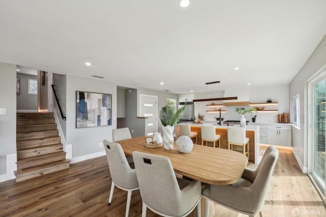dining space featuring light wood finished floors, baseboards, visible vents, recessed lighting, and stairs