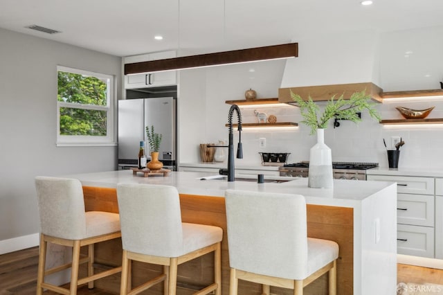 kitchen featuring a sink, freestanding refrigerator, visible vents, decorative backsplash, and open shelves
