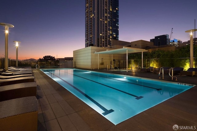pool at dusk featuring fence, a community pool, and central AC