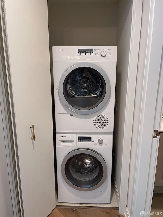 laundry room featuring laundry area, stacked washer / dryer, and wood finished floors