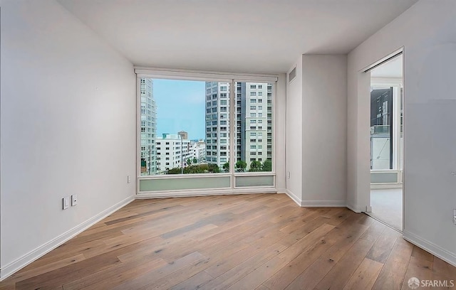 empty room featuring visible vents, baseboards, a view of city, and hardwood / wood-style floors