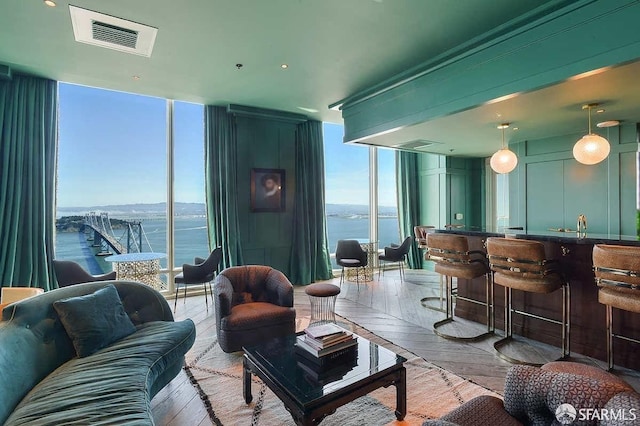 living room featuring a water view, indoor bar, expansive windows, visible vents, and parquet floors