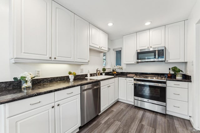 kitchen featuring white cabinets, dark stone countertops, sink, and appliances with stainless steel finishes