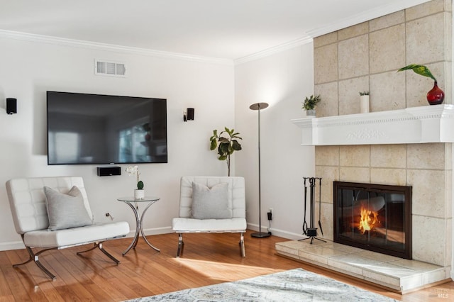 living area featuring a fireplace, hardwood / wood-style floors, and ornamental molding