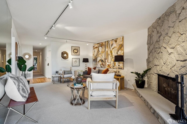 carpeted living room with rail lighting and a fireplace