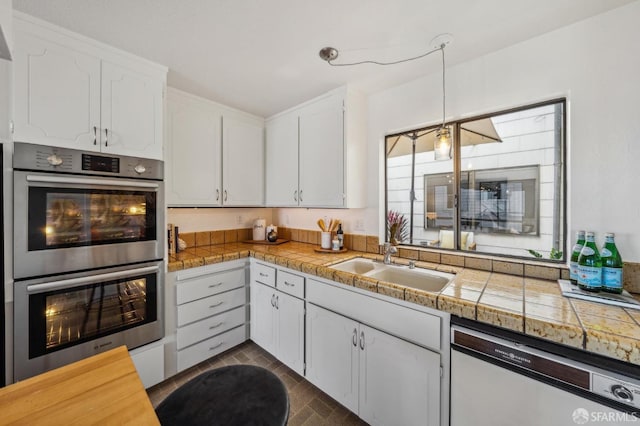 kitchen with decorative light fixtures, dishwasher, sink, white cabinetry, and stainless steel double oven