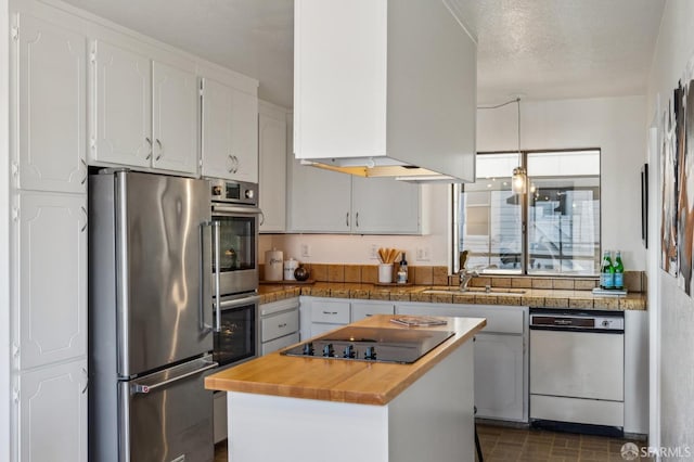 kitchen featuring white cabinets, a kitchen island, stainless steel appliances, sink, and butcher block countertops