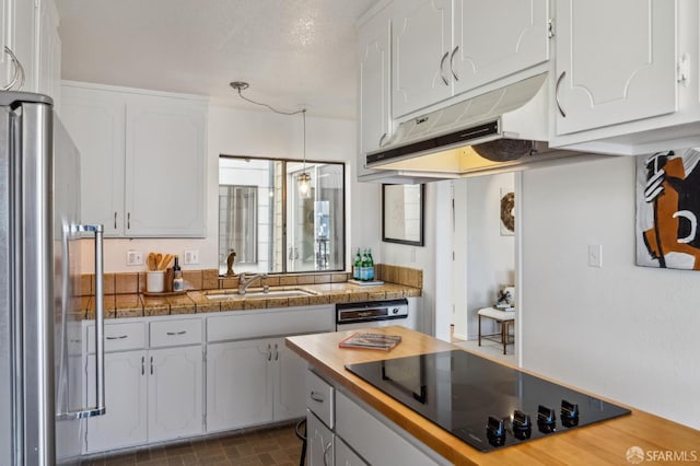 kitchen with white cabinets, stainless steel fridge, black electric stovetop, and sink