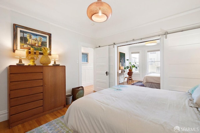 bedroom featuring a barn door, crown molding, and wood finished floors