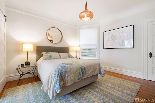 bedroom with dark wood-style floors, ornamental molding, and baseboards