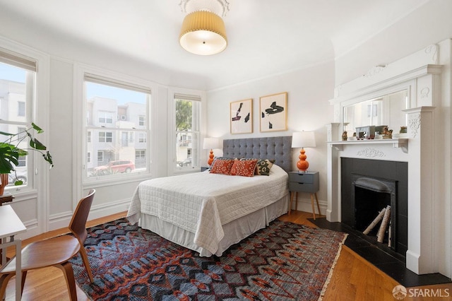 bedroom with dark wood-style flooring, a fireplace with flush hearth, and baseboards