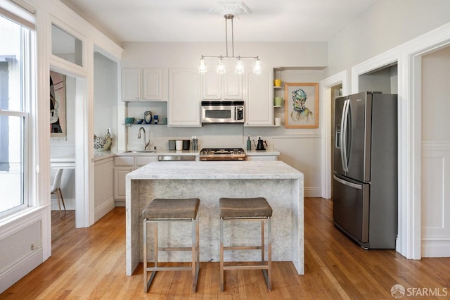 kitchen featuring open shelves, appliances with stainless steel finishes, decorative light fixtures, and white cabinets