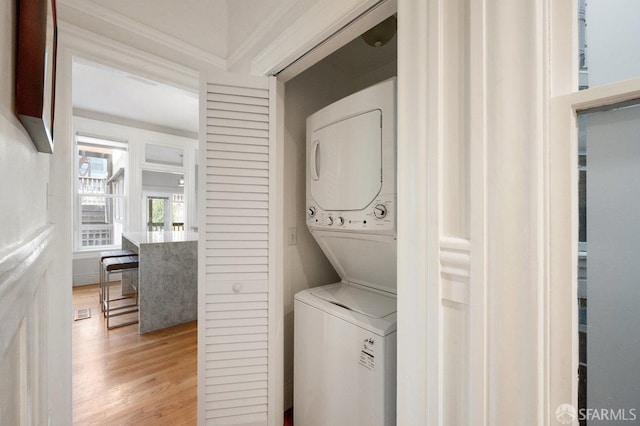 laundry room with stacked washer and dryer, laundry area, and light wood-style floors